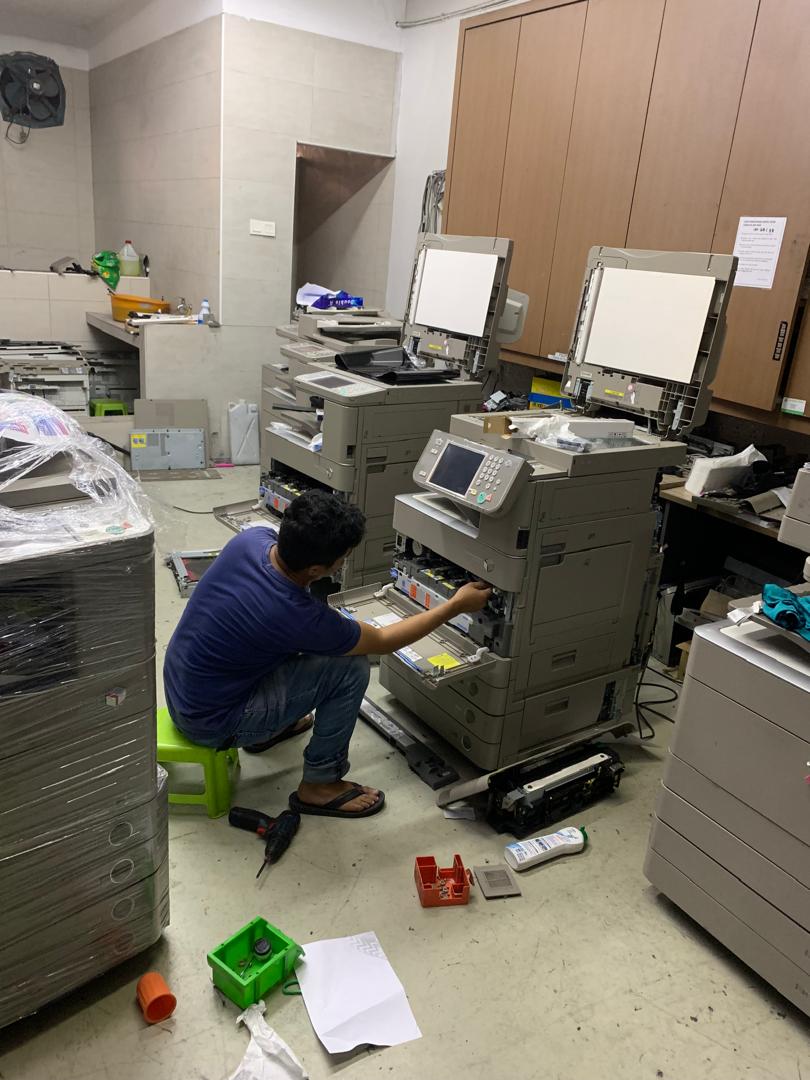 Technician servicing the internals of a Canon multifunction copier
