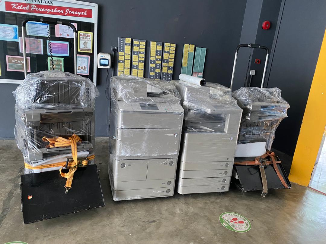 Four wrapped Canon copiers freshly delivered and strapped for transport